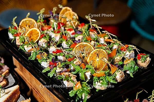 Delightful array of appetizers topped with fresh greens and citrus slices. ideal for summer gatherings or festive occasions, offering vibrant colors and flavors [IBR124626864]