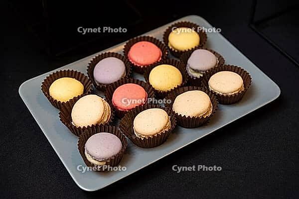 A variety of colorful macarons arranged on a plate. the pastel treats are set against a dark background, showcasing their vibrant hues and delicate textures [IBR124626867]