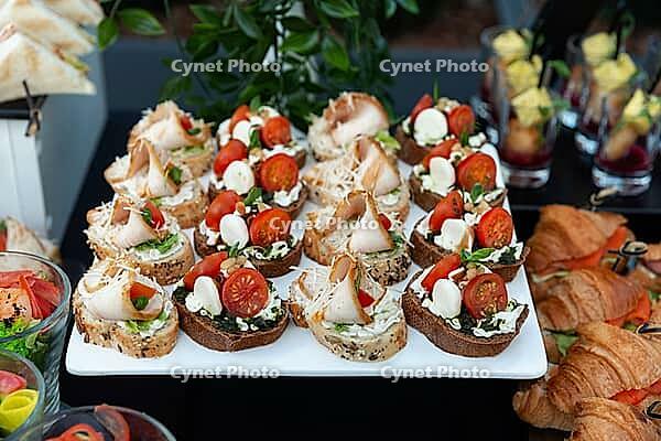 A beautifully arranged platter of gourmet canapés featuring fresh ingredients like cherry tomatoes, cheese, and assorted toppings. ideal for upscale gatherings or parties [IBR124626868]