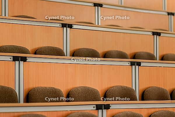 A spacious lecture hall featuring rows of empty, cushioned wooden seats. the arrangement provides a sense of order and anticipation, capturing the essence of academic settings [IBR124626894]