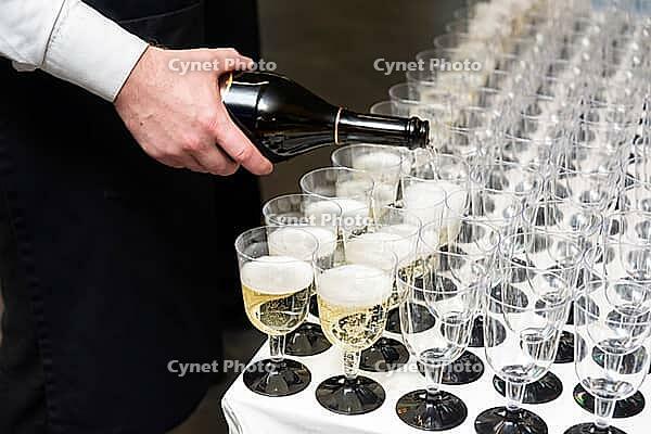 A person elegantly pours champagne into multiple crystal-clear glasses, creating an inviting atmosphere for a special event or celebration. each glass is meticulously lined up, promising a toast to memorable moments [IBR124626895]