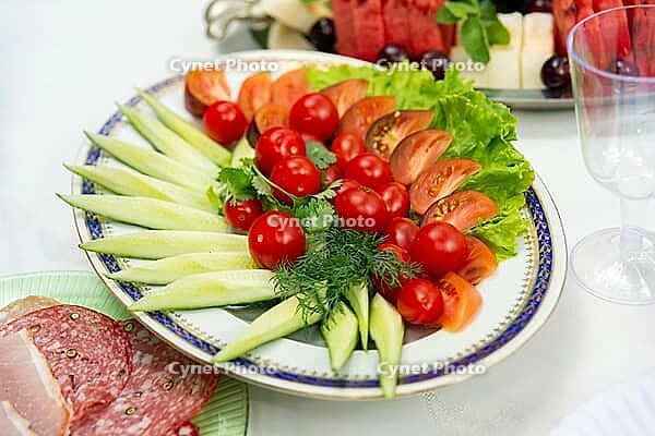 A colorful assortment of fresh vegetables, including cucumbers, tomatoes, and lettuce, arranged on a platter. perfect for parties or healthy eating occasions [IBR124626898]