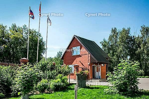 Kolomna, Russia - August 17, 2014 - Charming red brick house with flags in sunny garden setting [IBR124626902]
