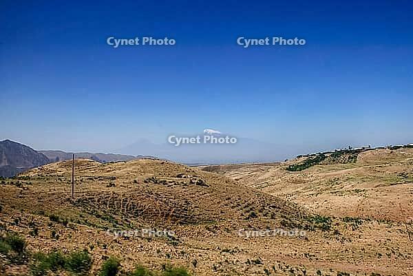 Distant view of snow-capped mountain under clear blue sky across arid landscape [IBR124626923]