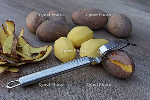 Peeled and unpeeled Laura potatoes with potato peeler, Kempen, North Rhine-Westphalia, Germany [IBR124629547]