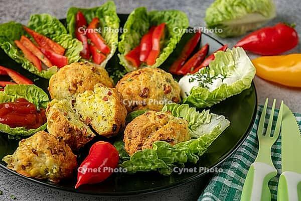 A plate of baked balls, pizza balls surrounded by lettuce leaves, pepper strips and dip [IBR124636272]