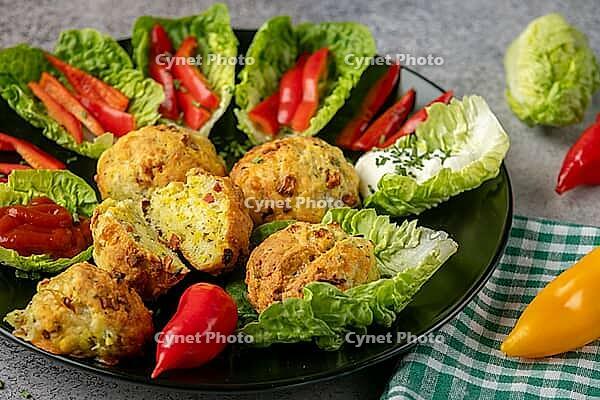 A plate of baked balls, pizza balls surrounded by lettuce leaves, pepper strips and dip [IBR124636273]