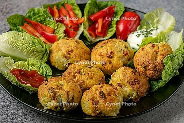 A plate of baked balls, pizza balls surrounded by lettuce leaves, pepper strips and dip [IBR124636274]