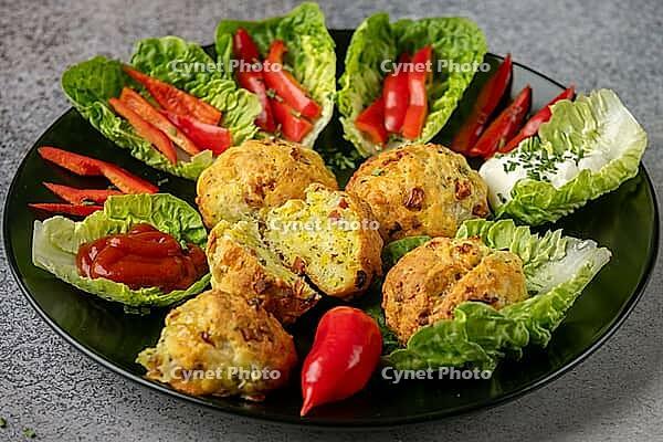 A plate of baked balls, pizza balls surrounded by lettuce leaves, pepper strips and dip [IBR124636275]