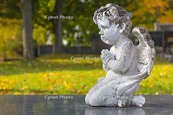Sculpture of a little angel on a tomb in cemetery. Graz, Austria [IBR124636286]