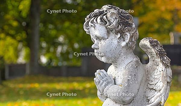 Sculpture of a little angel on a tomb in cemetery. Graz, Austria [IBR124636287]
