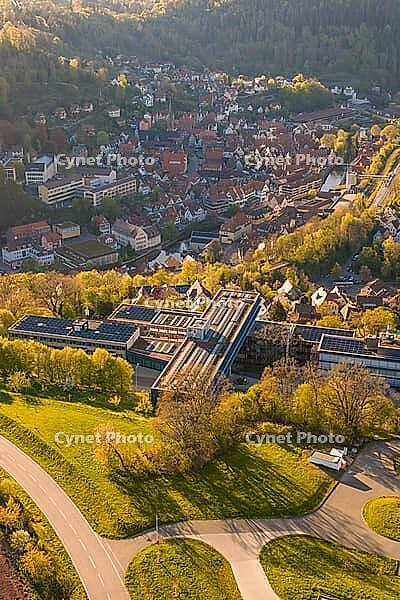 Aerial view of a settlement with traditional houses surrounded by green hills and sunlight, Calw District Office, Calw District, Germany [IBR124642835]