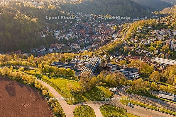 Aerial view of a village in a hilly, green landscape, roads and fields visible in sunshine, Calw District Office, Calw District, Germany [IBR124642836]
