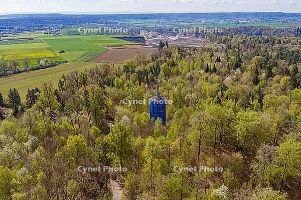 A water tower stands out in the middle of a thick forest full of spring vegetation, Aidlingen, Böblingen district, Germany [IBR124642848]