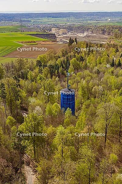 Dense green vegetation surrounds a blue water tower in a spring forest, Aidlingen, Böblingen district, Germany [IBR124642849]