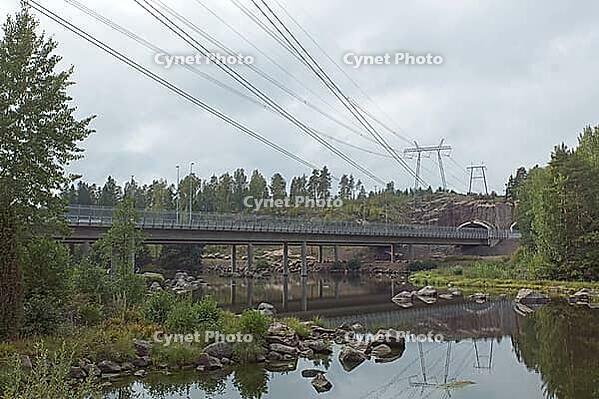 View of Ahvenkoski highway bridge over rocky rapids of the Kymijoki river in cloudy autumn weather, Pyhtää, Finland [IBR124748941]