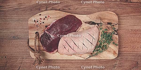 Fresh raw duck breasts, on a wooden chopping board, with herbs and spices, no people [IBR124748949]