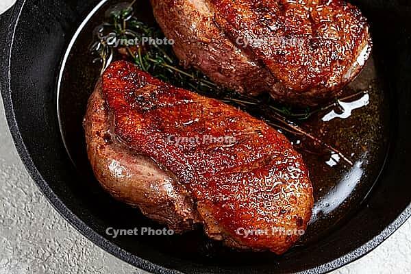 Roast duck breast, in a frying pan, with spices and herbs, close-up, no people [IBR124748956]