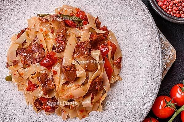 Food, Delicious asian udon dish with vegetables, meat, salt and spices on a ceramic plate on a dark concrete background [IBR124773702]