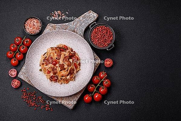 Food, Delicious asian udon dish with vegetables, meat, salt and spices on a ceramic plate on a dark concrete background [IBR124773708]