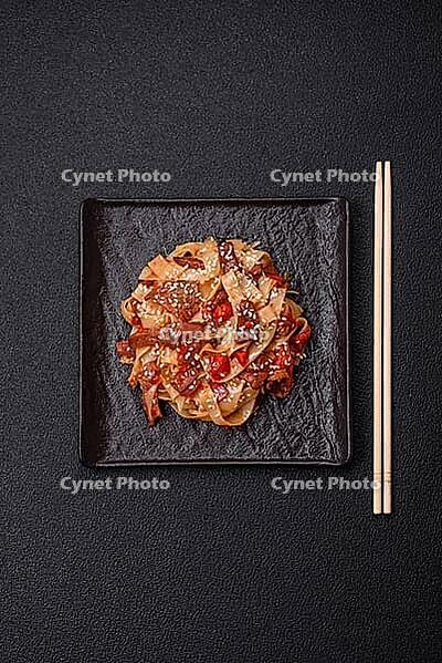 Food, Delicious asian udon dish with vegetables, meat, salt and spices on a ceramic plate on a dark concrete background [IBR124773709]