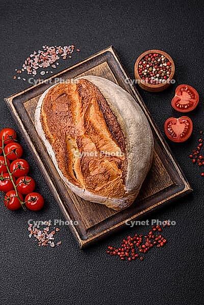 Food, A loaf of brown bread with grains of cereals on a wooden cutting board on a dark concrete background [IBR124773756]