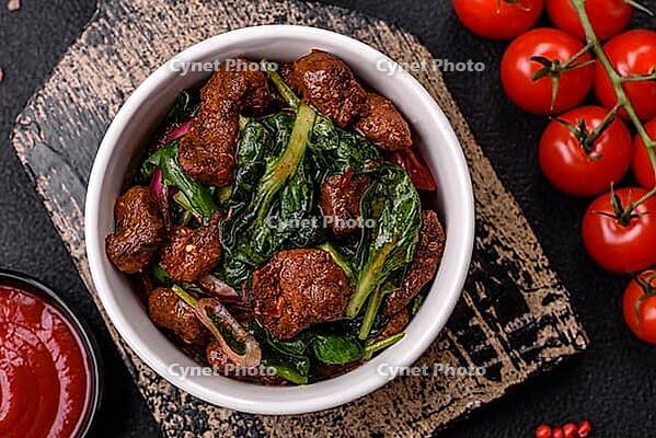 Food, Delicious warm salad with pieces of meat, spinach, tomatoes, salt, spices and herbs on a dark concrete background [IBR124773766]