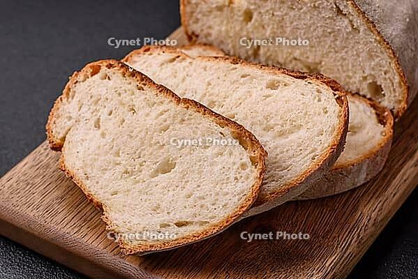 Food, A loaf of brown bread with grains of cereals on a wooden cutting board on a dark concrete background [IBR124773777]