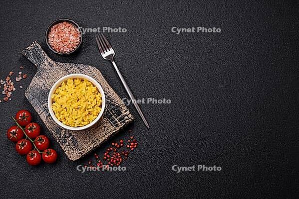 Food, Delicious boiled yellow rice with turmeric, salt and spices on a dark concrete background [IBR124773784]