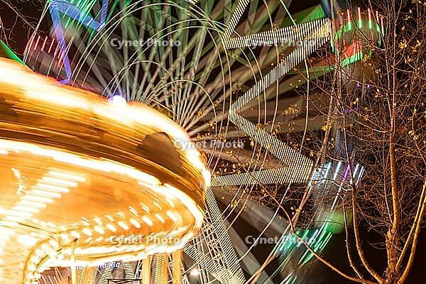 Colourful striped light illuminated spinning ferris wheel in motion moving at night [IBR124817843]