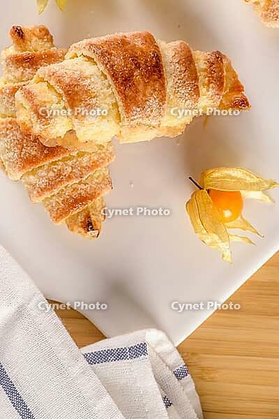 Small croissant with physalis fruits in white ceramic tray, homemade cakes on wooden table top [IBR124817873]