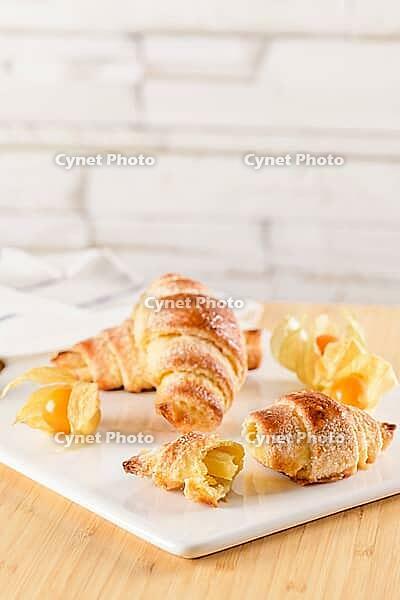 Small croissant with physalis fruits in white ceramic tray, homemade cakes on wooden table top [IBR124817887]