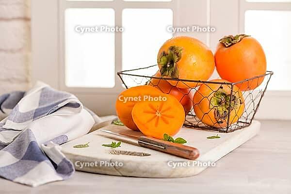 Delicious fresh persimmon fruit on kitchen countertop [IBR124817888]