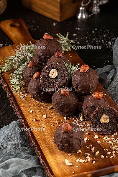 Dark chocolate truffles with hazelnuts over wooden cutting board [IBR124817894]
