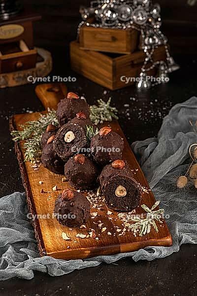 Dark chocolate truffles with hazelnuts over wooden cutting board [IBR124817895]