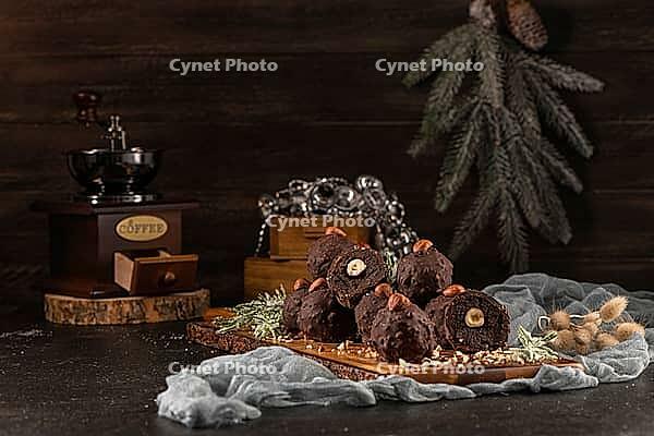 Dark chocolate truffles with hazelnuts over wooden cutting board [IBR124817904]