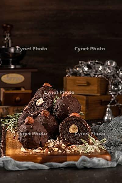 Dark chocolate truffles with hazelnuts over wooden cutting board [IBR124817906]