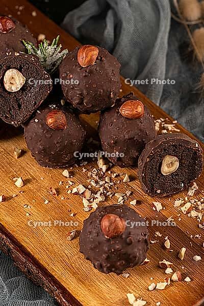 Dark chocolate truffles with hazelnuts over wooden cutting board [IBR124817913]