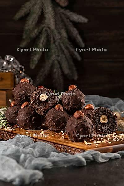 Dark chocolate truffles with hazelnuts over wooden cutting board [IBR124817914]
