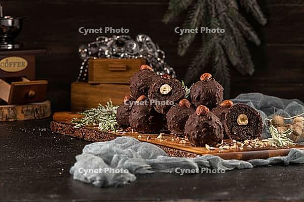 Dark chocolate truffles with hazelnuts over wooden cutting board [IBR124817915]