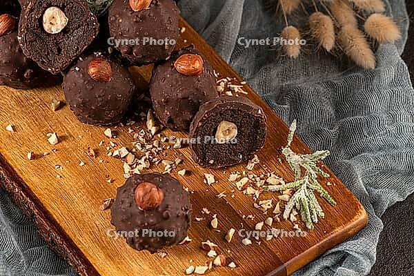 Dark chocolate truffles with hazelnuts over wooden cutting board [IBR124817920]