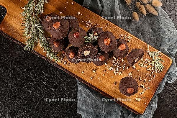 Dark chocolate truffles with hazelnuts over wooden cutting board [IBR124817934]