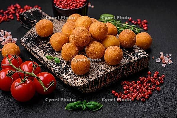 Food, Delicious fried potato balls with breaded mozzarella, salt, spices and herbs on a dark concrete background [IBR124842037]