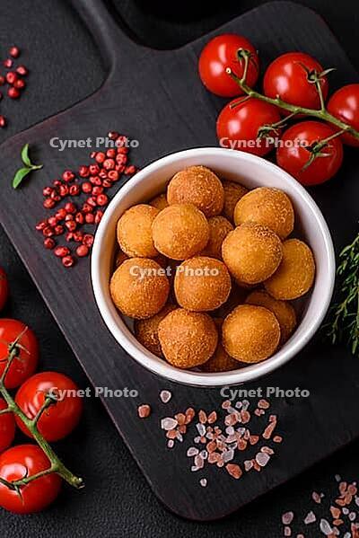 Food, Delicious fried potato balls with breaded mozzarella, salt, spices and herbs on a dark concrete background [IBR124842038]