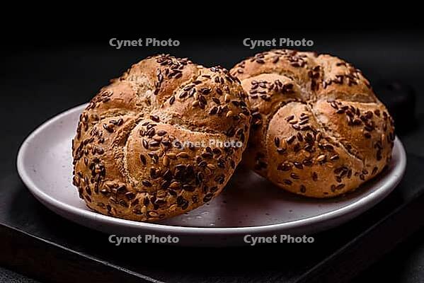 Food, Delicious freshly baked crispy bun or kaiser roll with sesame seeds on dark concrete background [IBR124842048]
