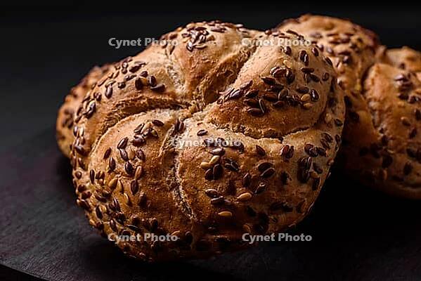 Food, Delicious freshly baked crispy bun or kaiser roll with sesame seeds on dark concrete background [IBR124842050]