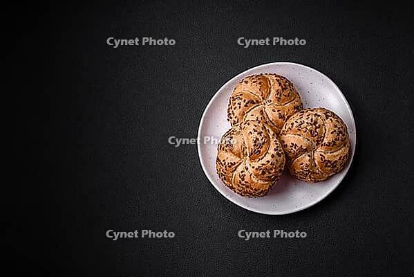 Food, Delicious freshly baked crispy bun or kaiser roll with sesame seeds on dark concrete background [IBR124842051]