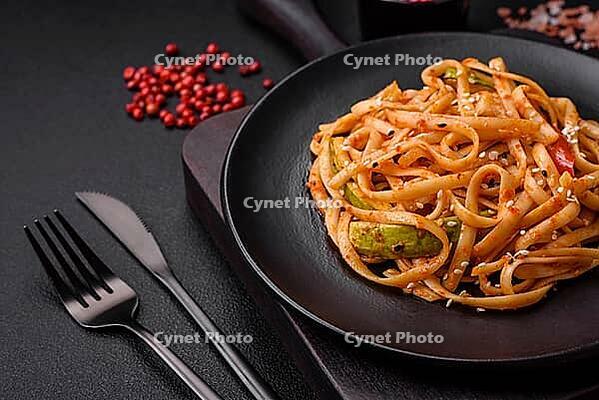Food, Delicious asian udon dish with vegetables, mushrooms, salt and spices on a ceramic plate on a dark concrete background [IBR124842057]
