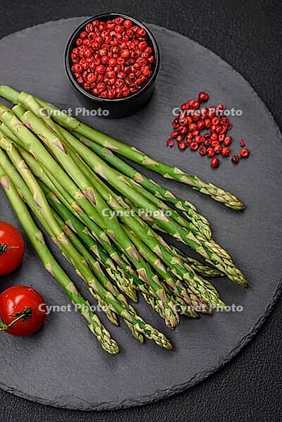 Food, Delicious fresh sprigs of asparagus on a dark textured background. Ingredients for a healthy vegetarian meal [IBR124842065]