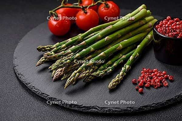 Food, Delicious fresh sprigs of asparagus on a dark textured background. Ingredients for a healthy vegetarian meal [IBR124842068]